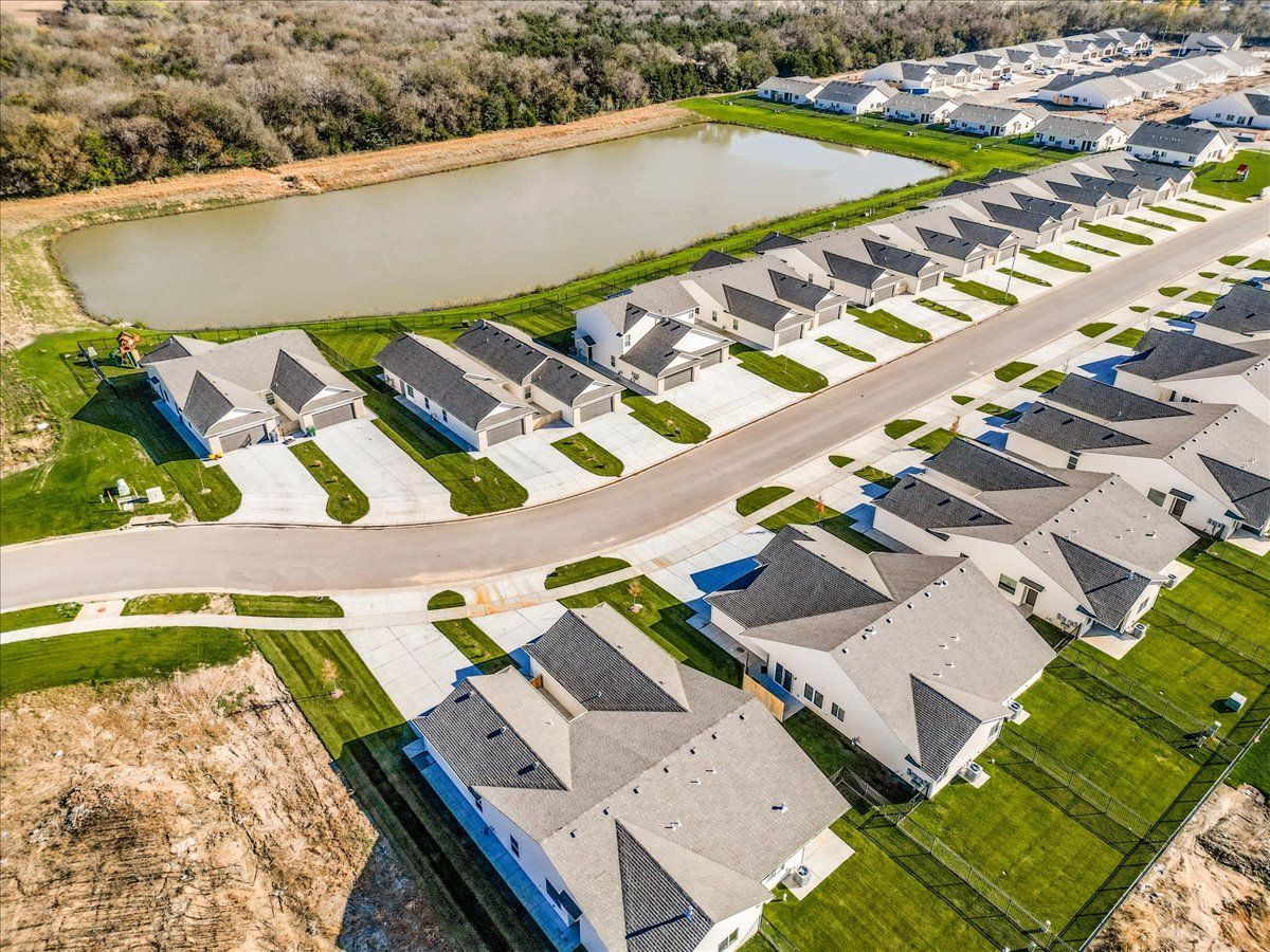 An aerial view of a residential neighborhood with a pond in the middle.