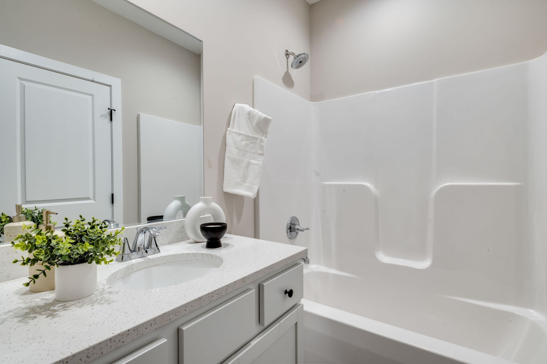 A bathroom with a sink , tub , mirror and shower.