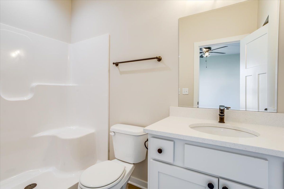A bathroom with a toilet , sink , shower and mirror.