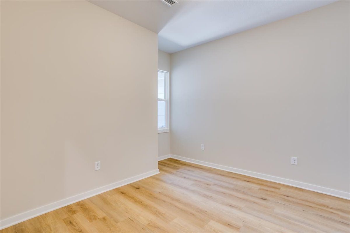 An empty room with hardwood floors and white walls.