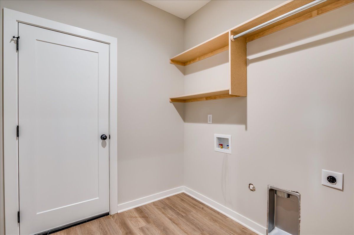 A laundry room with a door , shelves , and a dog door.