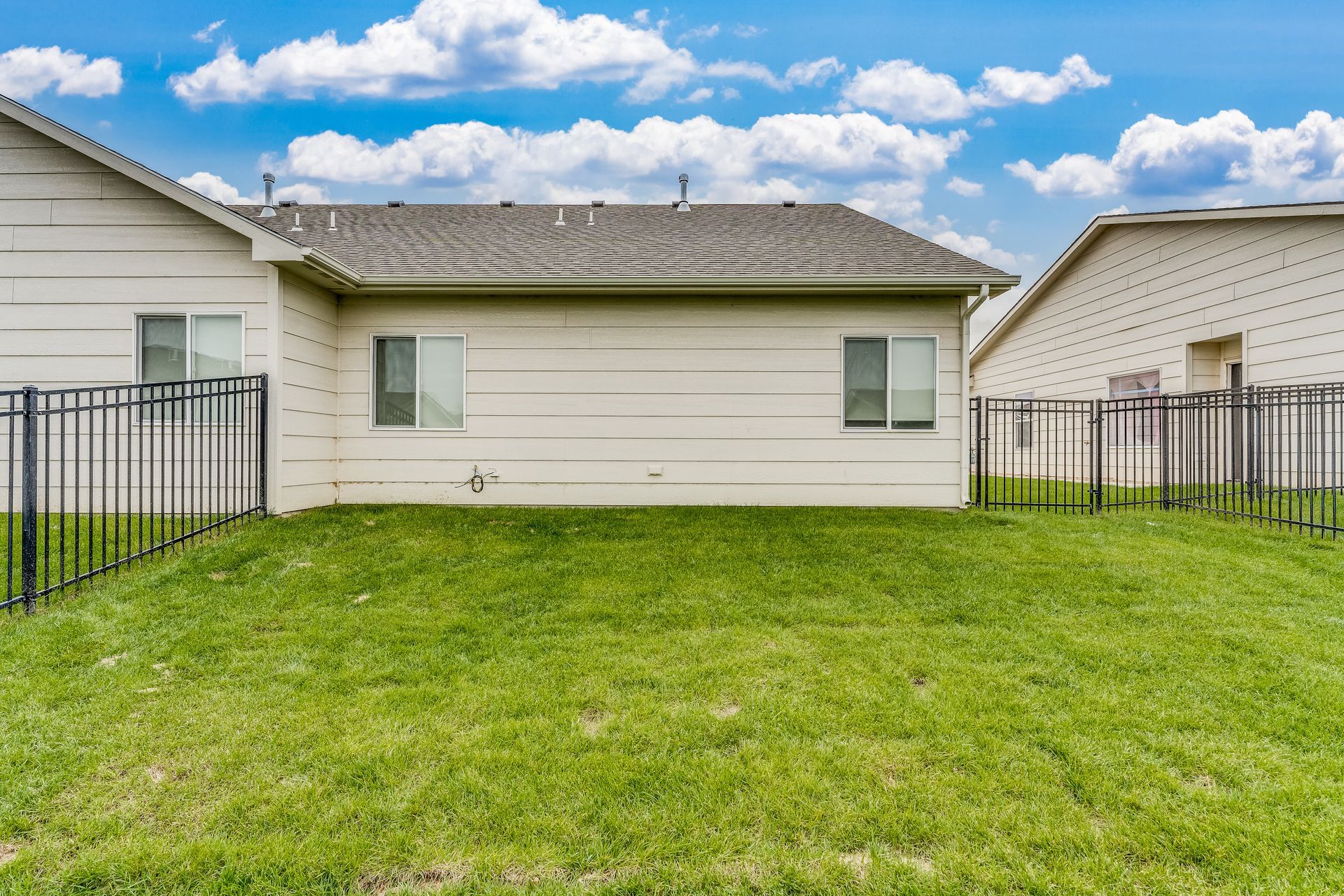 The backyard of a house with a fence and a lot of grass.