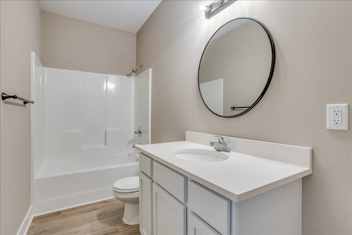 A bathroom with a sink , toilet , bathtub and mirror.