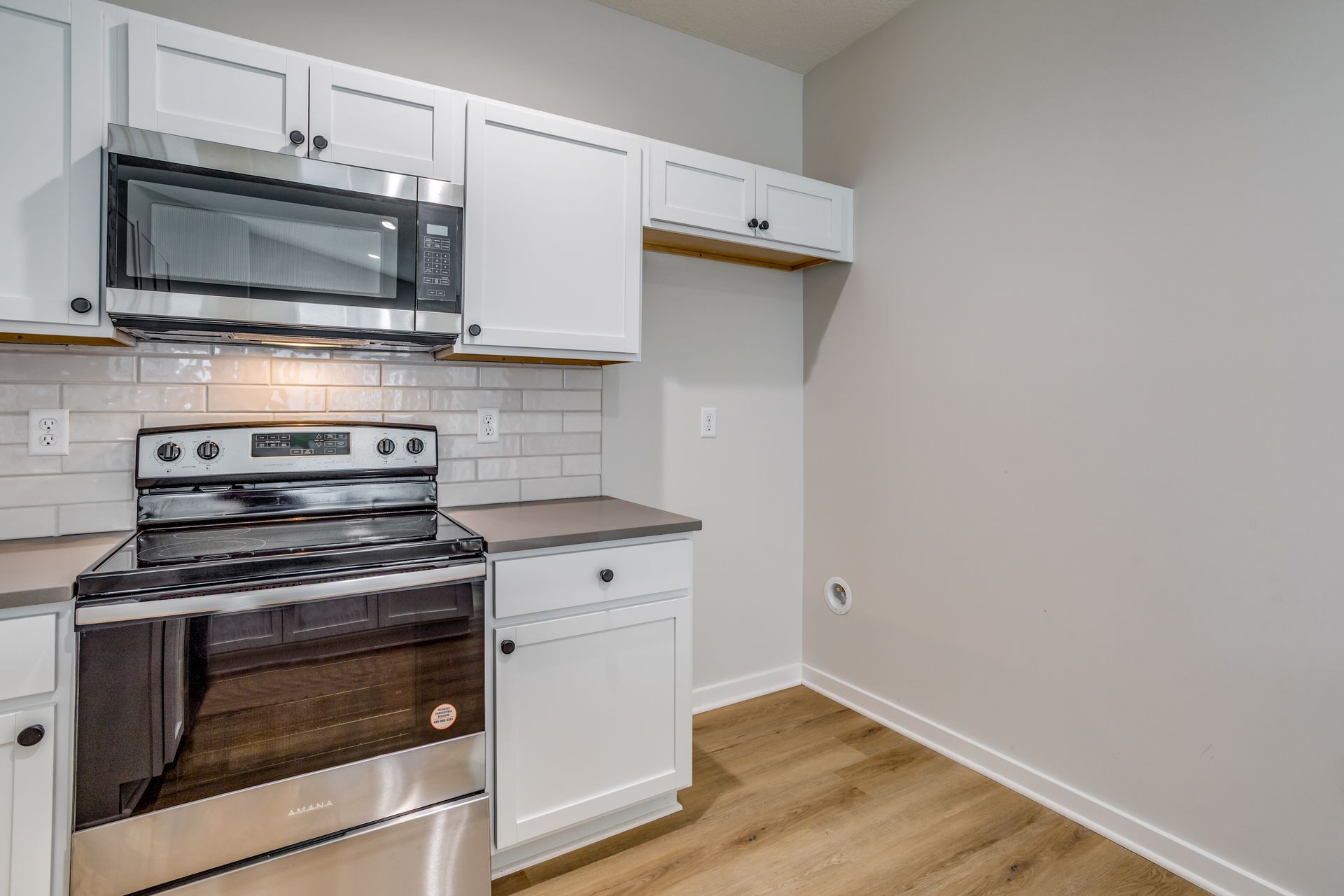 A kitchen with stainless steel appliances and white cabinets.