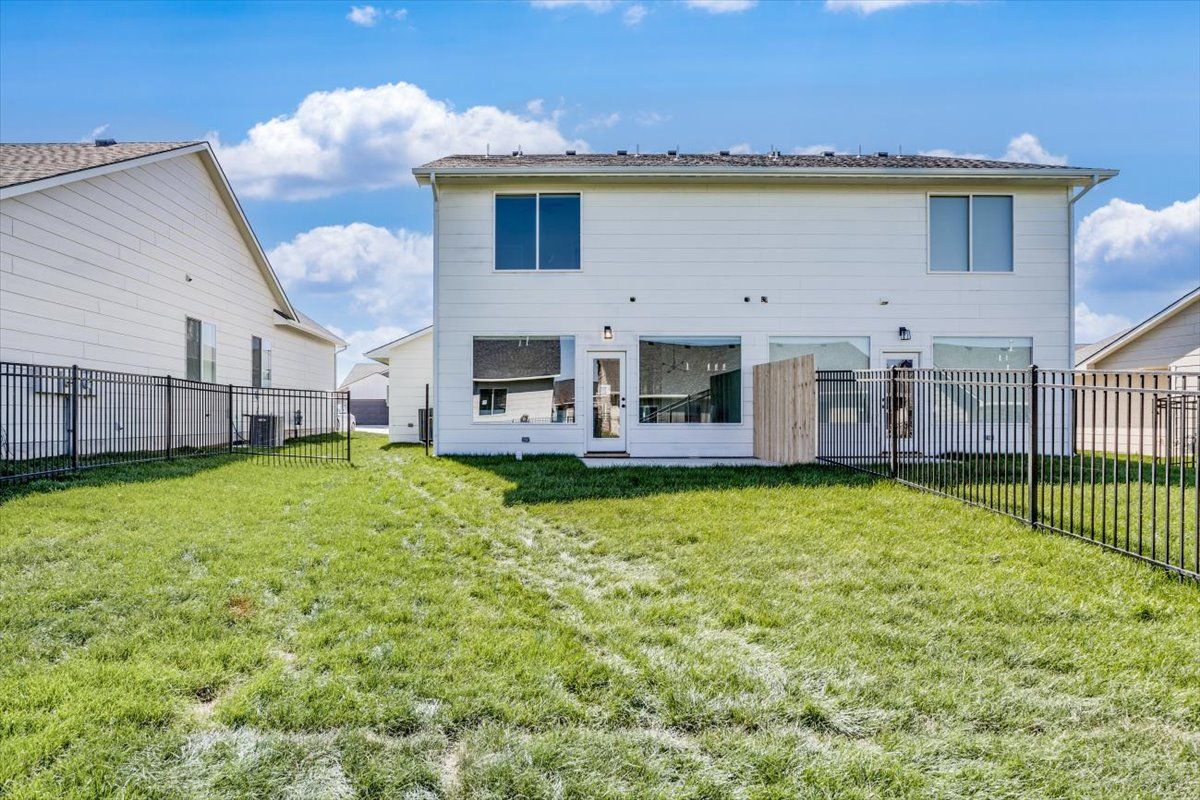 The backyard of a house with a fence and a lot of grass.