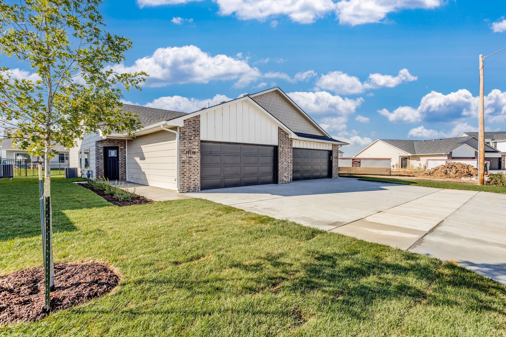 A house with two garages and a tree in front of it.