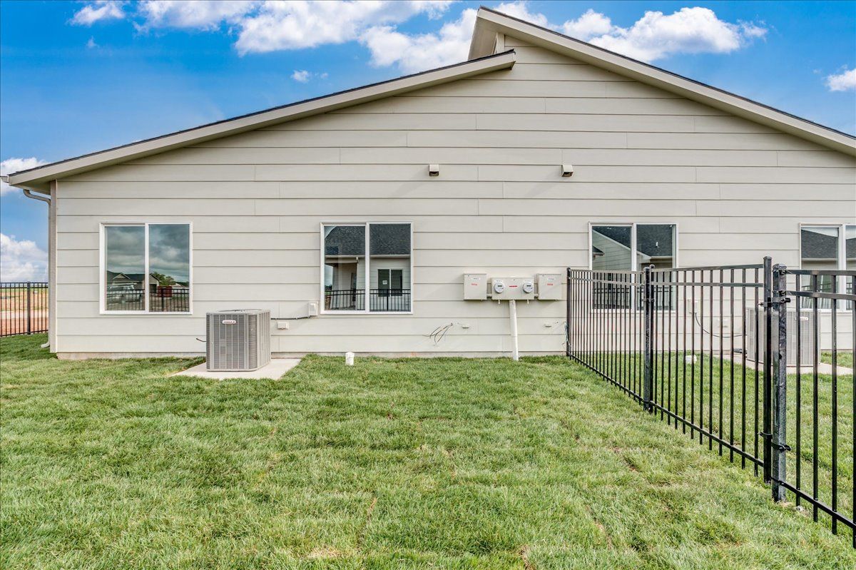 The backyard of a house with a fence and a lot of grass.