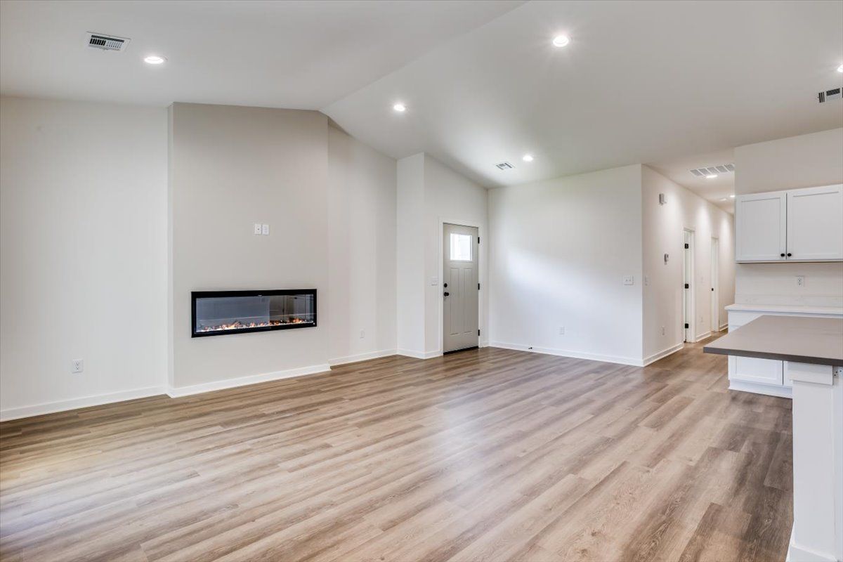 An empty living room with hardwood floors and a fireplace.