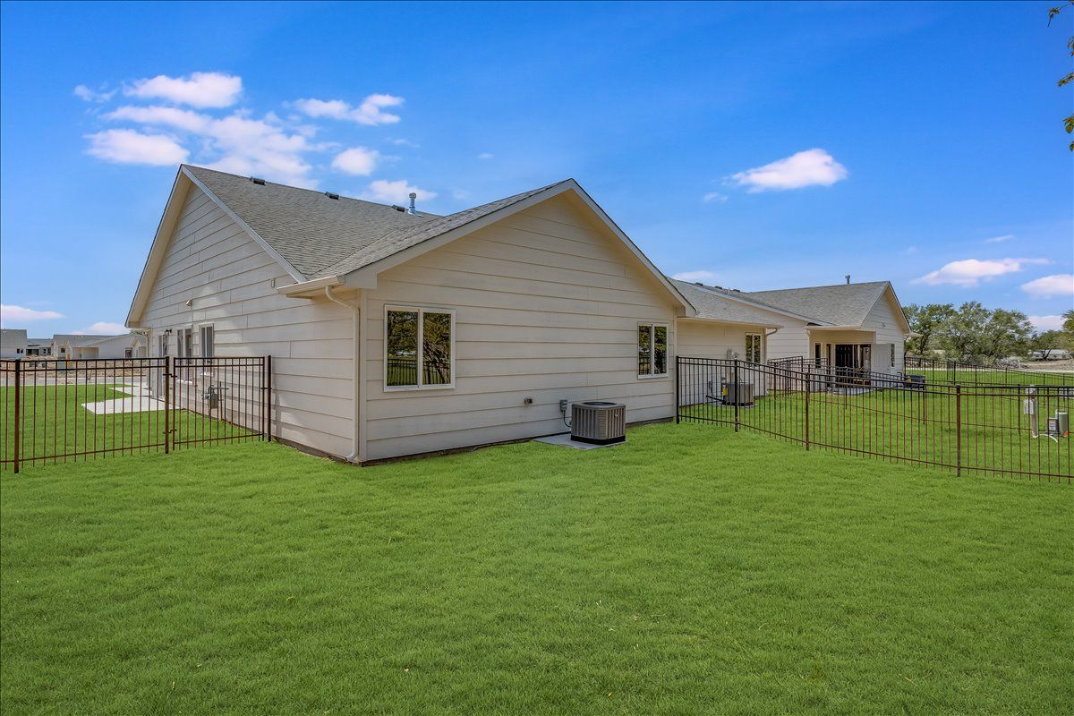 The backyard of a house with a fence and a lot of grass.