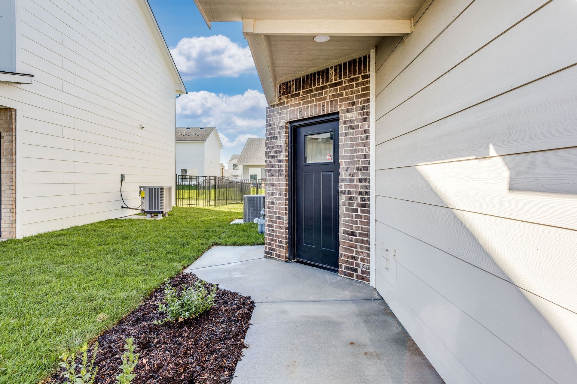 The front door of a house with a brick wall and a black door.