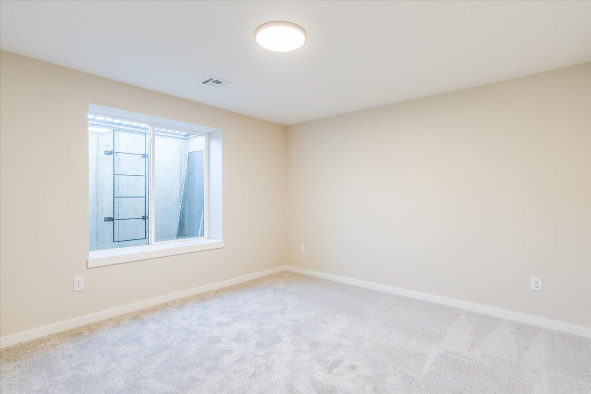 An empty bedroom with a window and a light on the ceiling.
