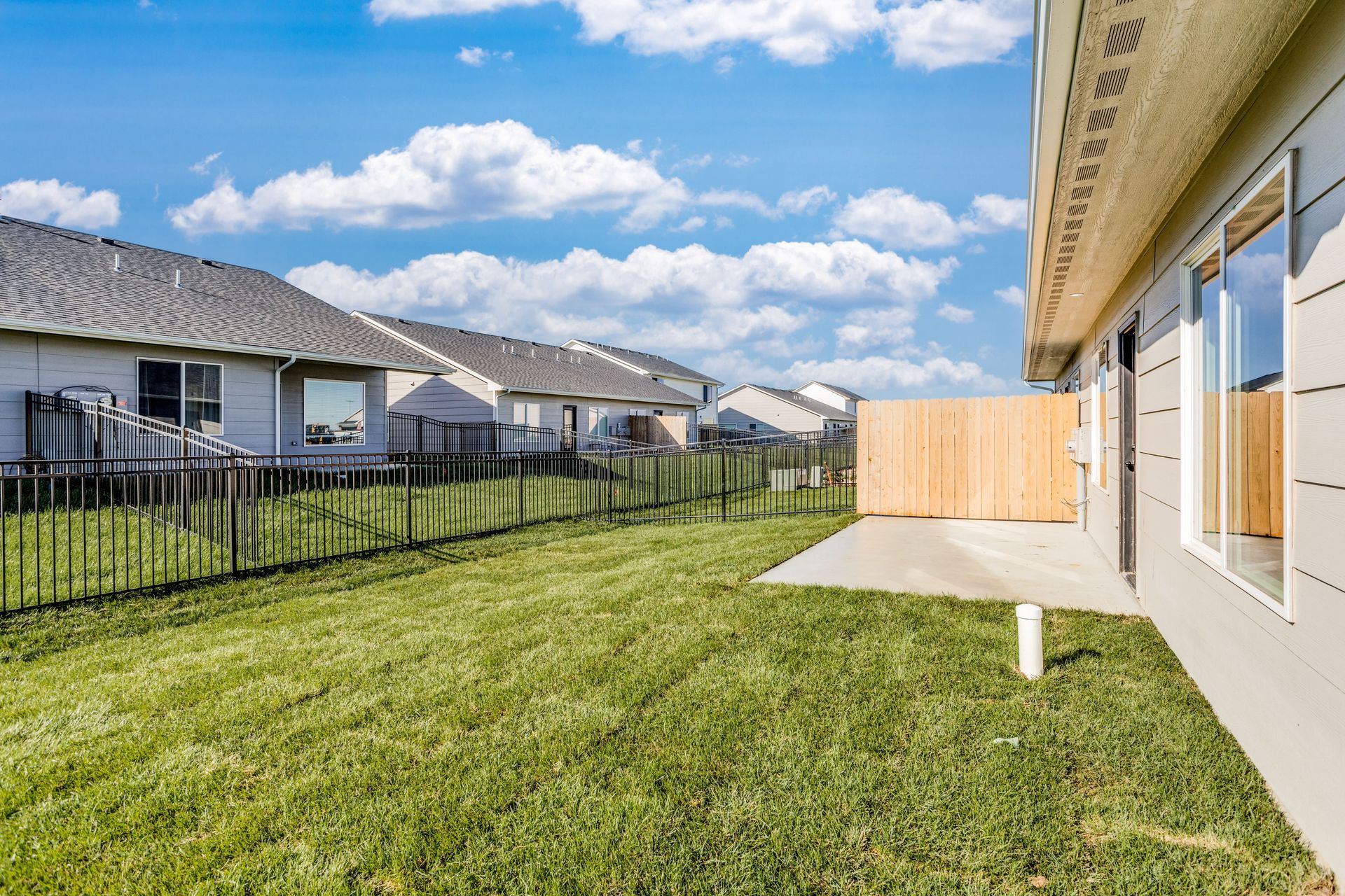 A backyard of a house with a fence and a lot of grass.