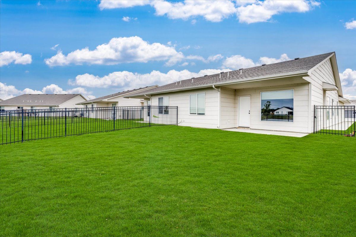 A house with a fence and a large lawn in front of it.