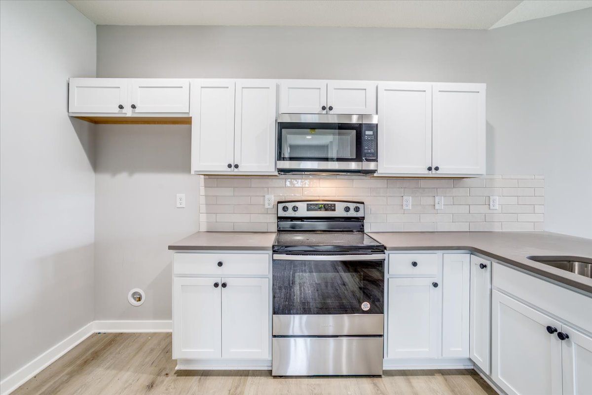 A kitchen with white cabinets and stainless steel appliances.
