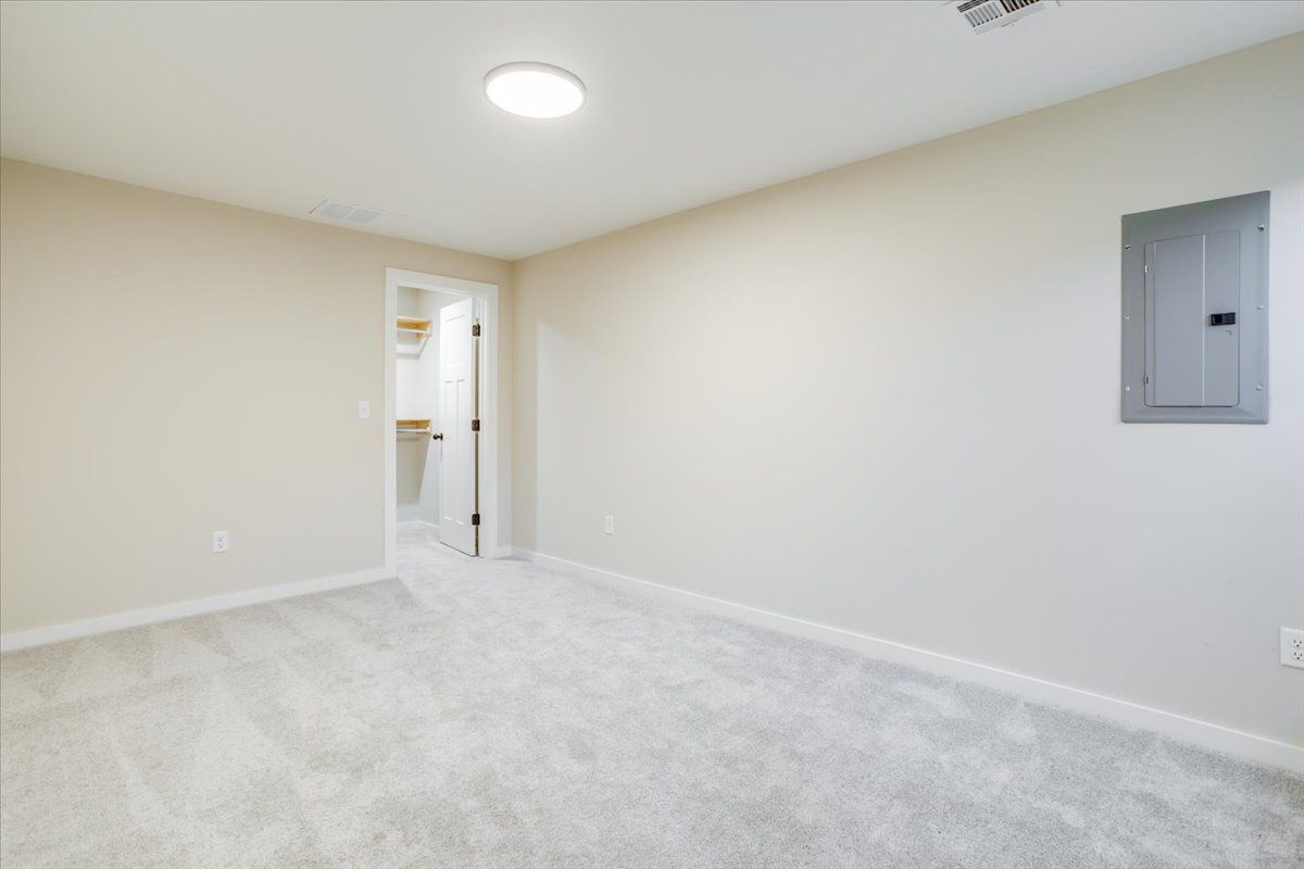 An empty room with a light on the ceiling and a door leading to a bathroom.