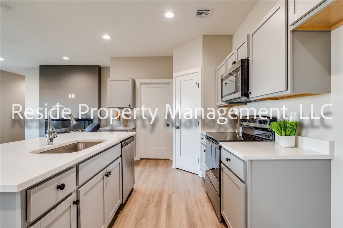 A kitchen with white cabinets and stainless steel appliances is for sale.