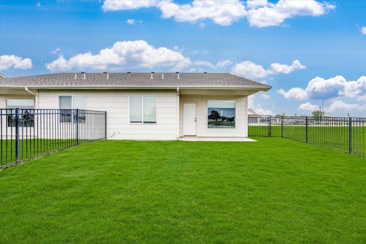 A white house with a large lawn and a fence in front of it.