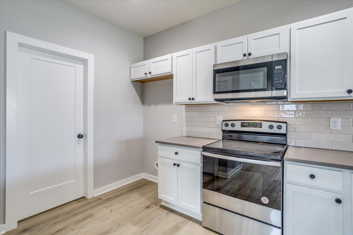 A kitchen with stainless steel appliances and white cabinets.