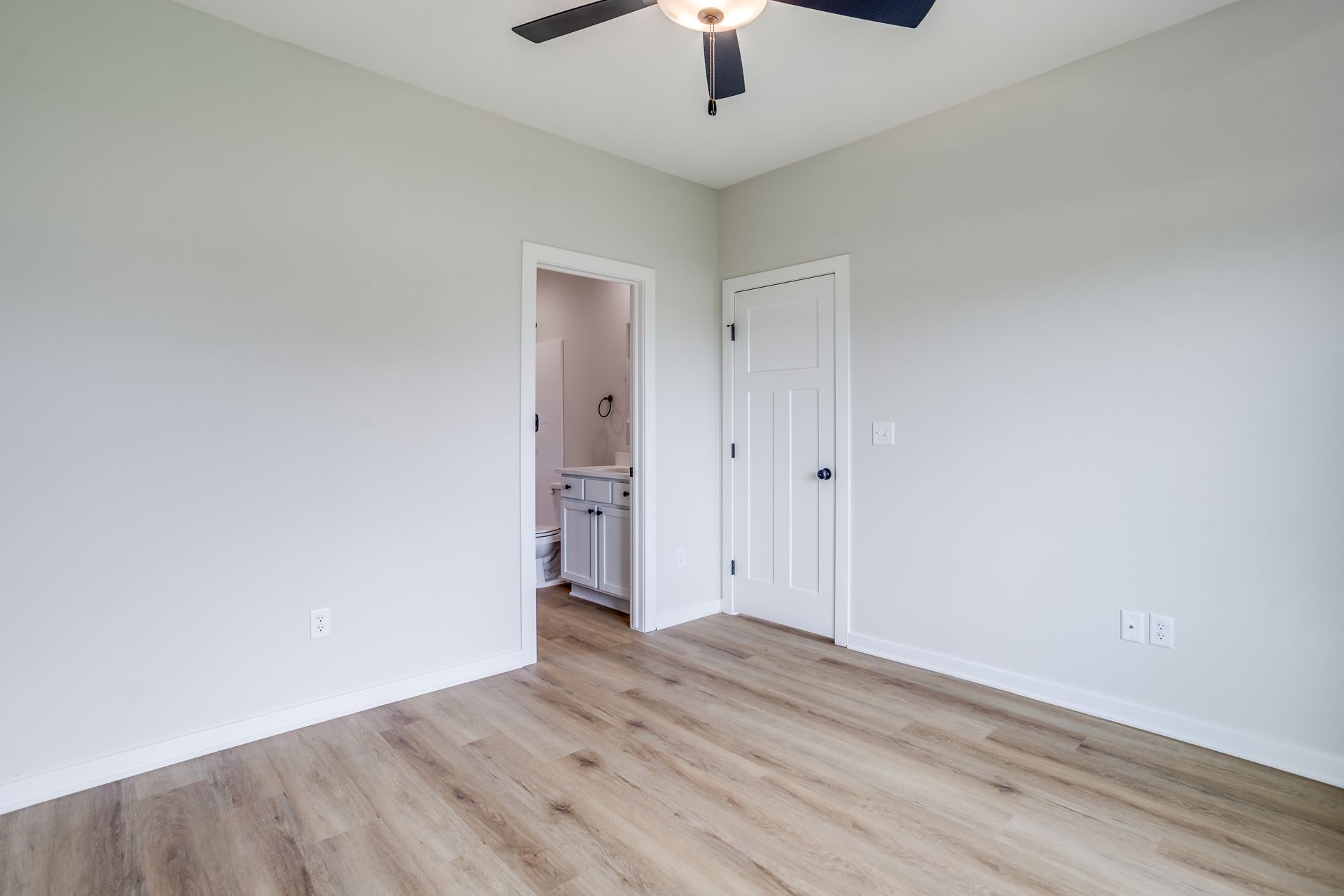 An empty bedroom with hardwood floors and a ceiling fan.