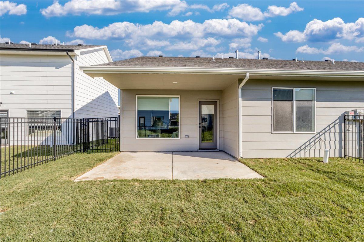 The backyard of a house with a patio and a fence.