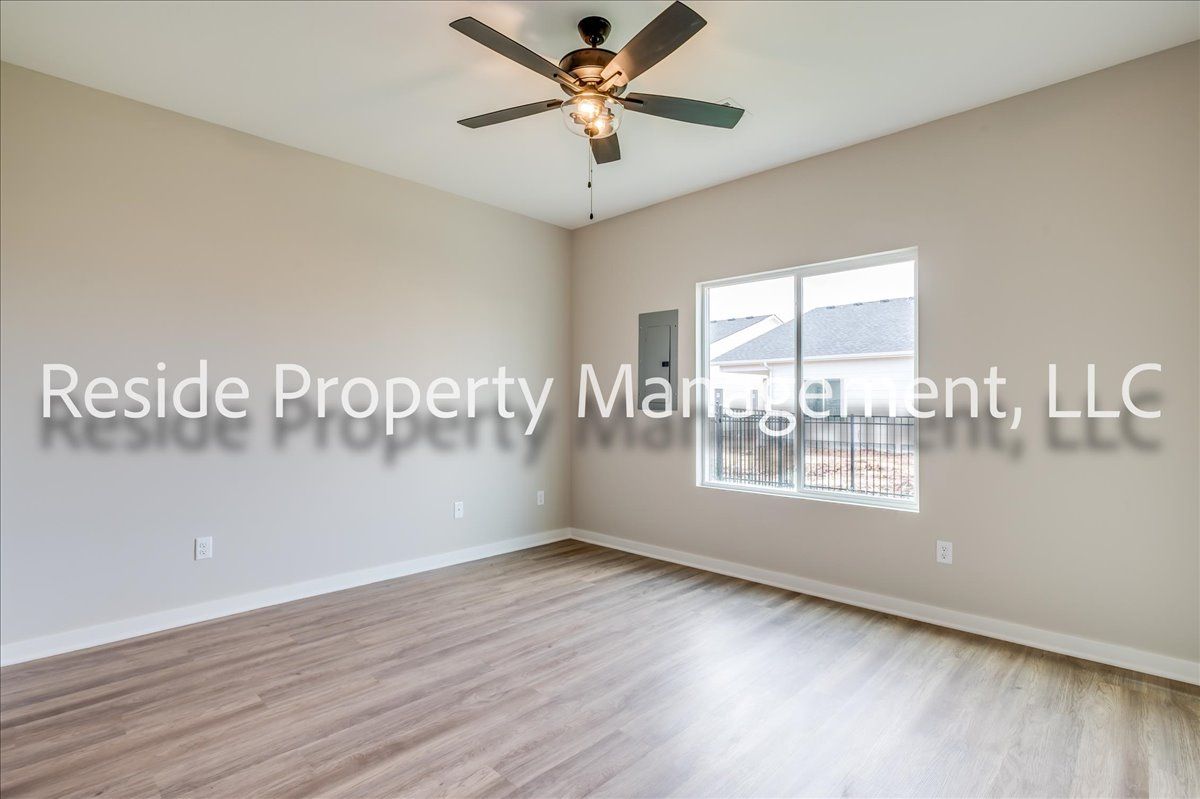 An empty room with a ceiling fan and a window