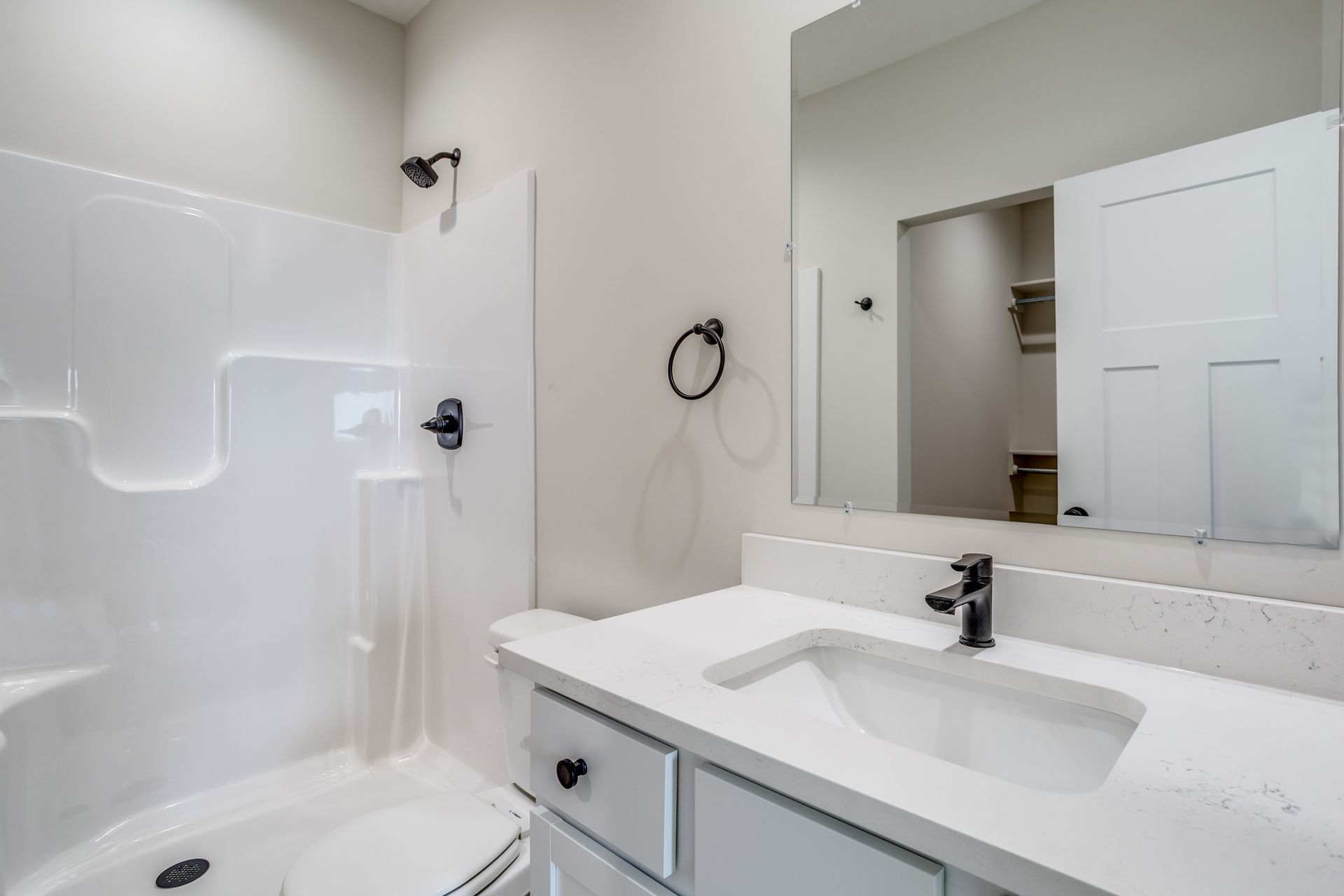 A bathroom with a sink , toilet , shower and mirror.
