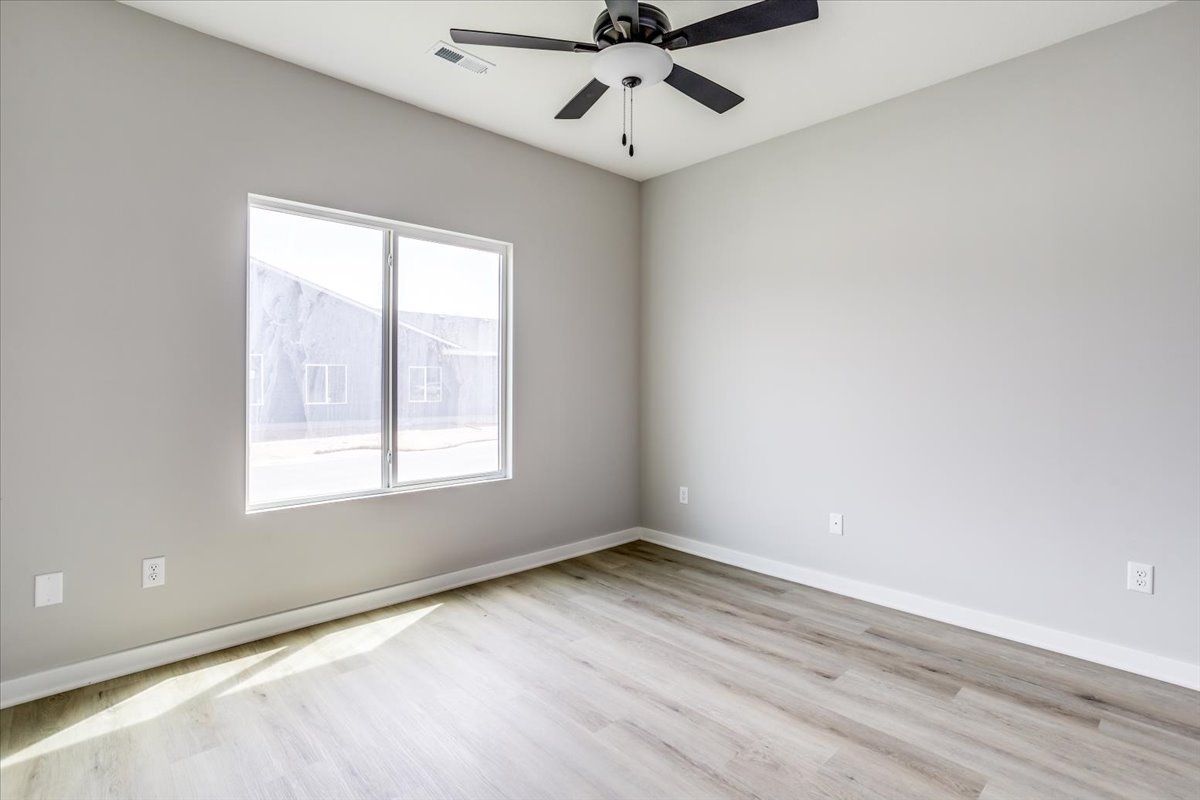 An empty room with a ceiling fan and a window.