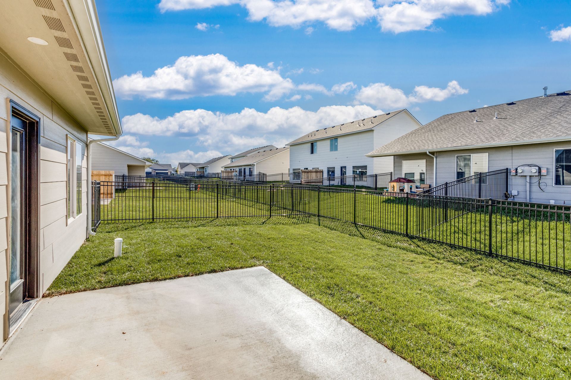 The backyard of a house with a fence and a patio.