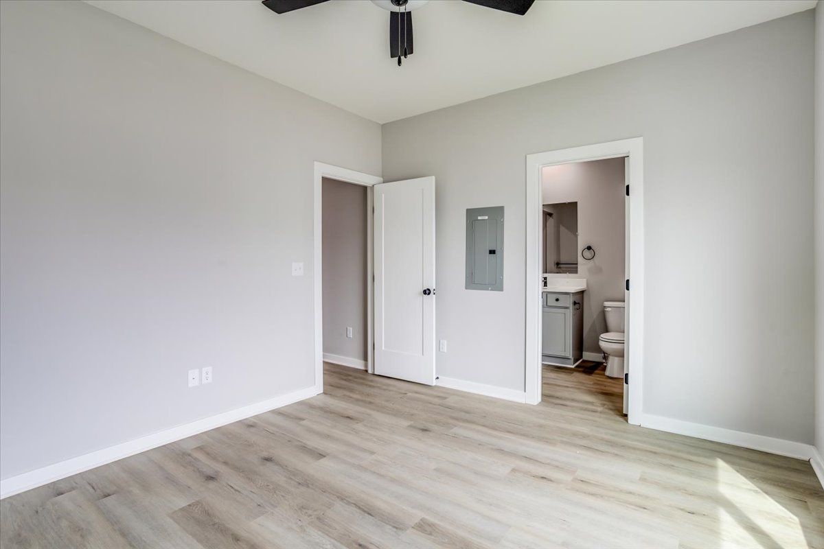 An empty bedroom with hardwood floors and a ceiling fan.