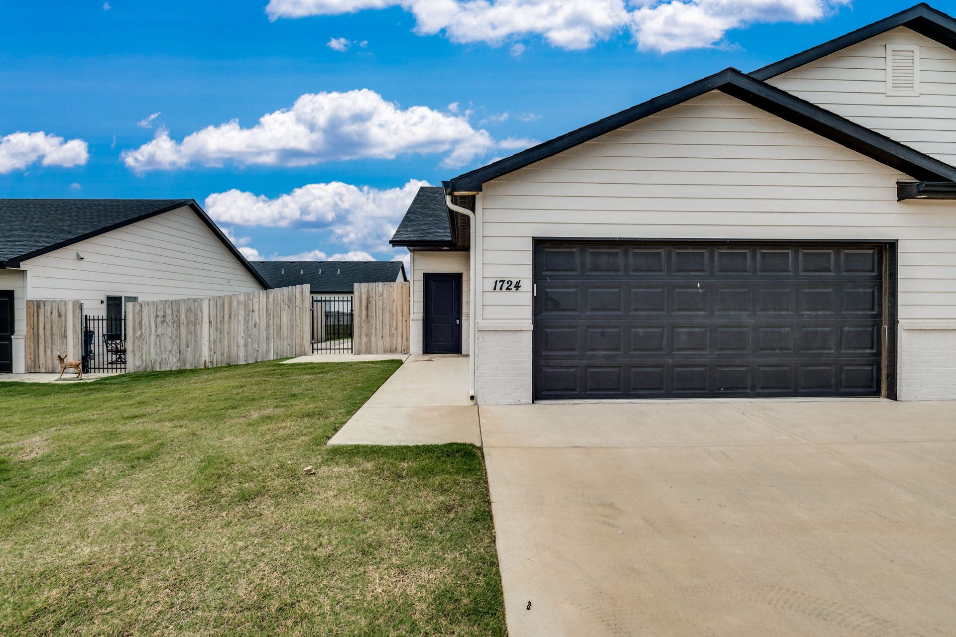 A white house with a black garage door is for sale.