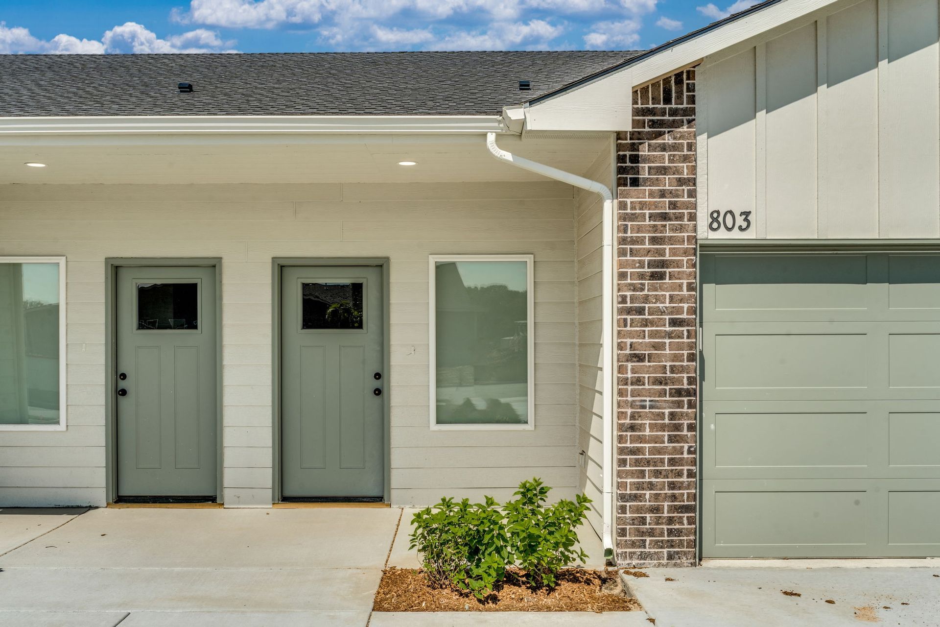 The front of a house with two doors and a garage.