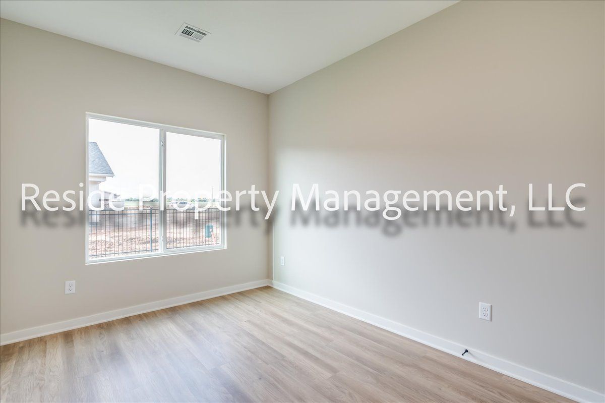 An empty bedroom with hardwood floors and a window.