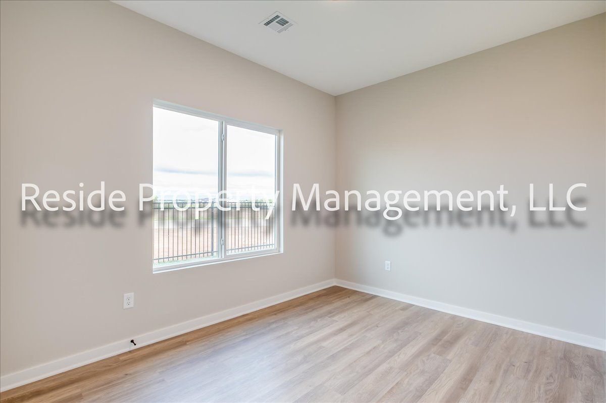 An empty bedroom with hardwood floors and two windows.