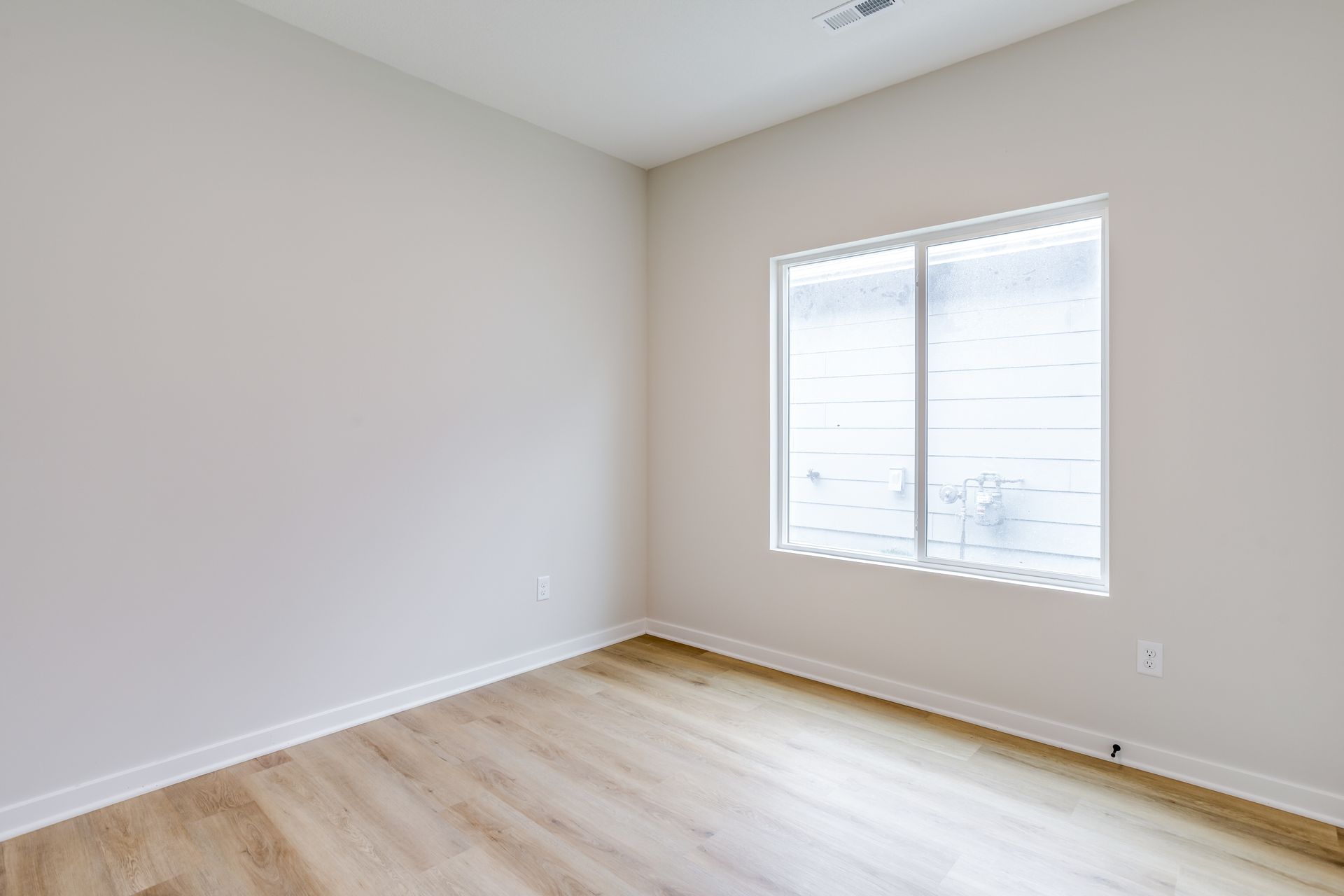 An empty room with hardwood floors and two windows.