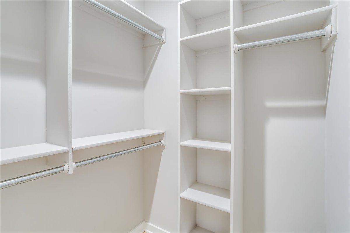 A walk in closet with lots of shelves and hanging clothes.