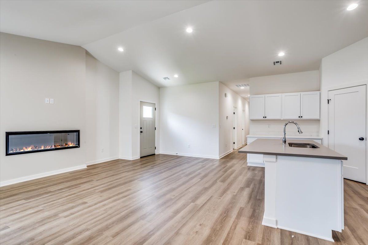 An empty living room with hardwood floors and a fireplace.