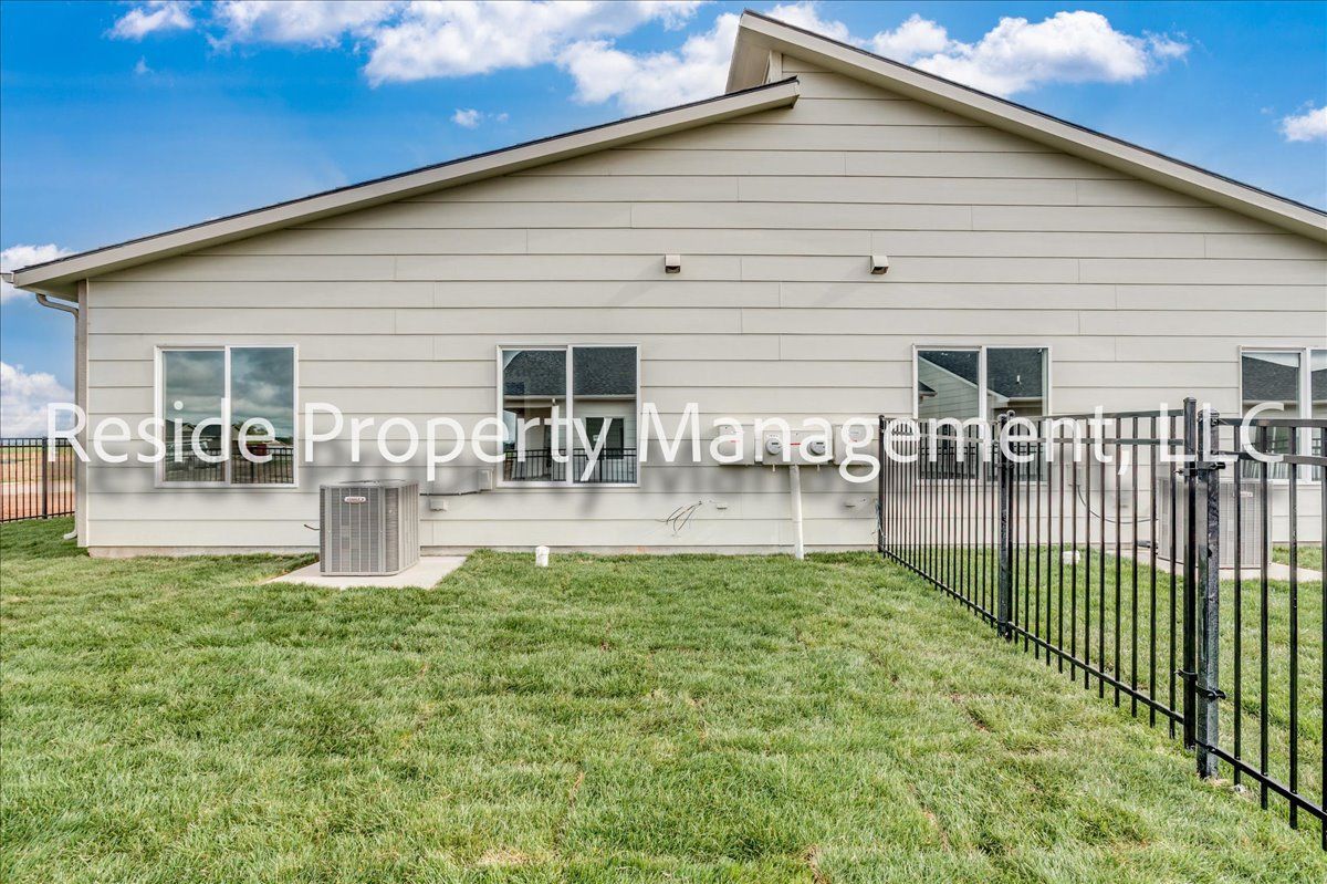 The back of a house with a fence in front of it.