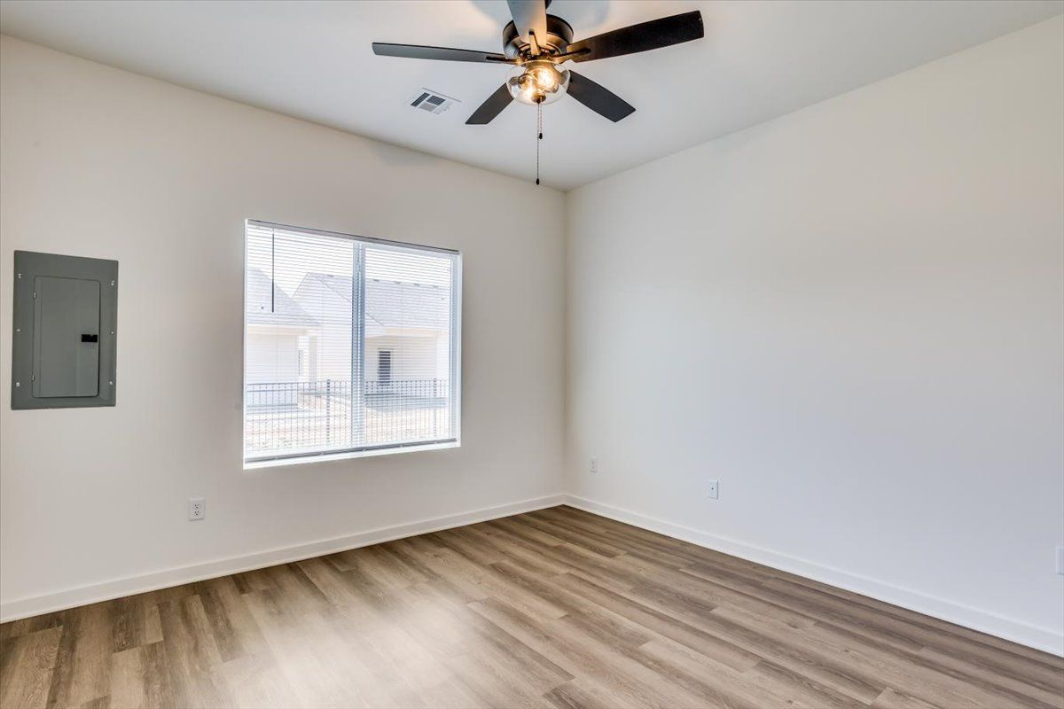 An empty room with a ceiling fan and a window.
