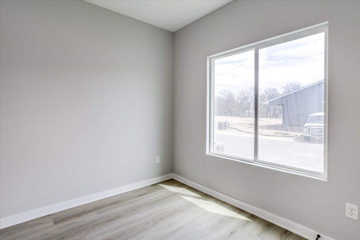 An empty room with a large window and a wooden floor.