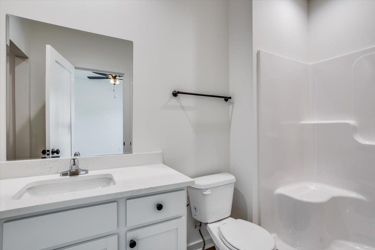 A bathroom with a toilet , sink , mirror and shower.