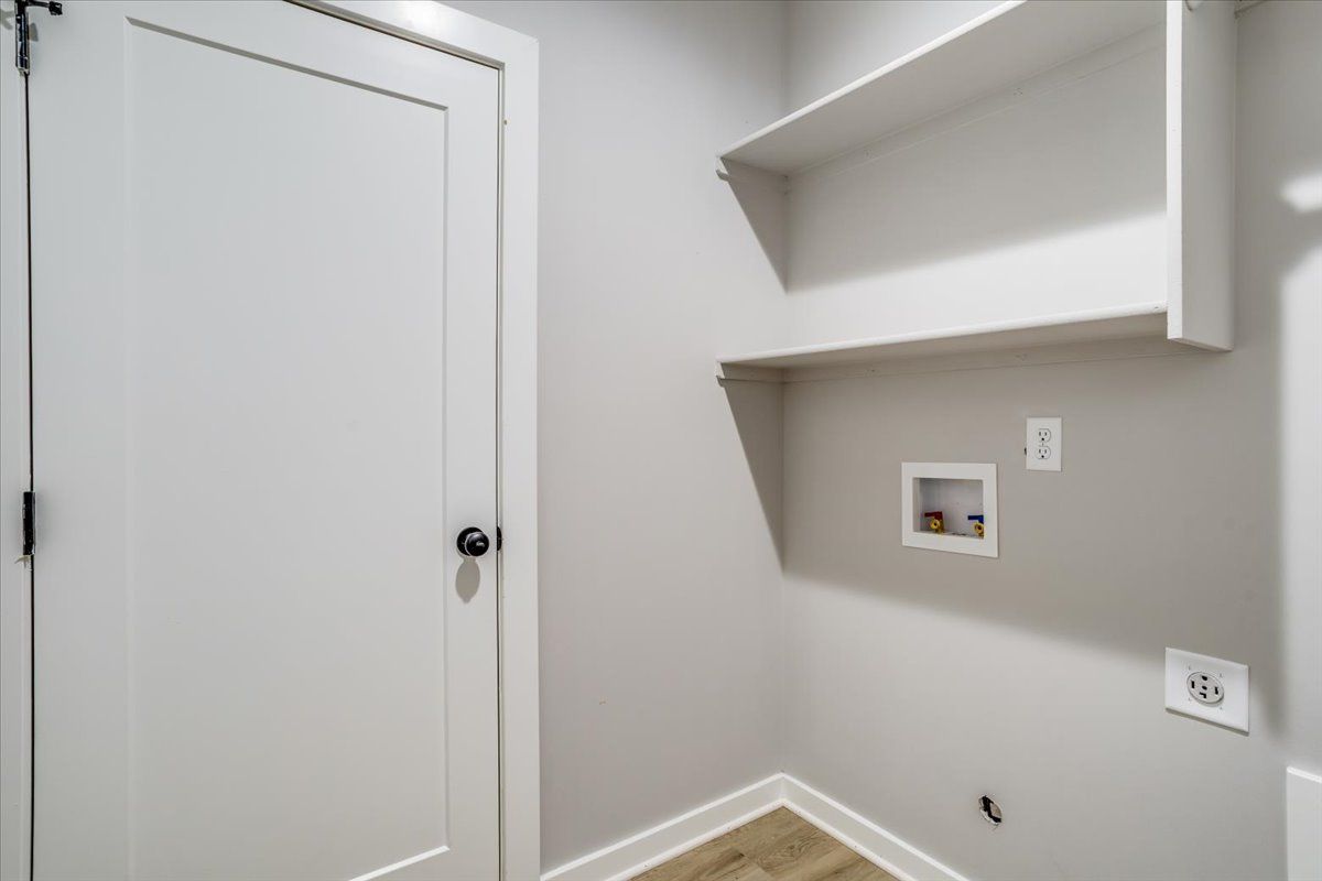A laundry room with a door , shelves , and a washer and dryer.