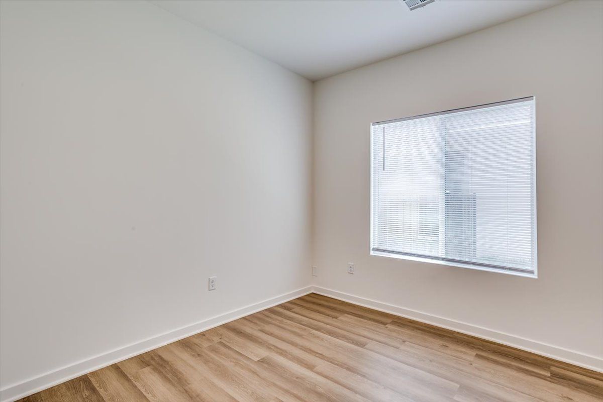 An empty room with hardwood floors and a window.