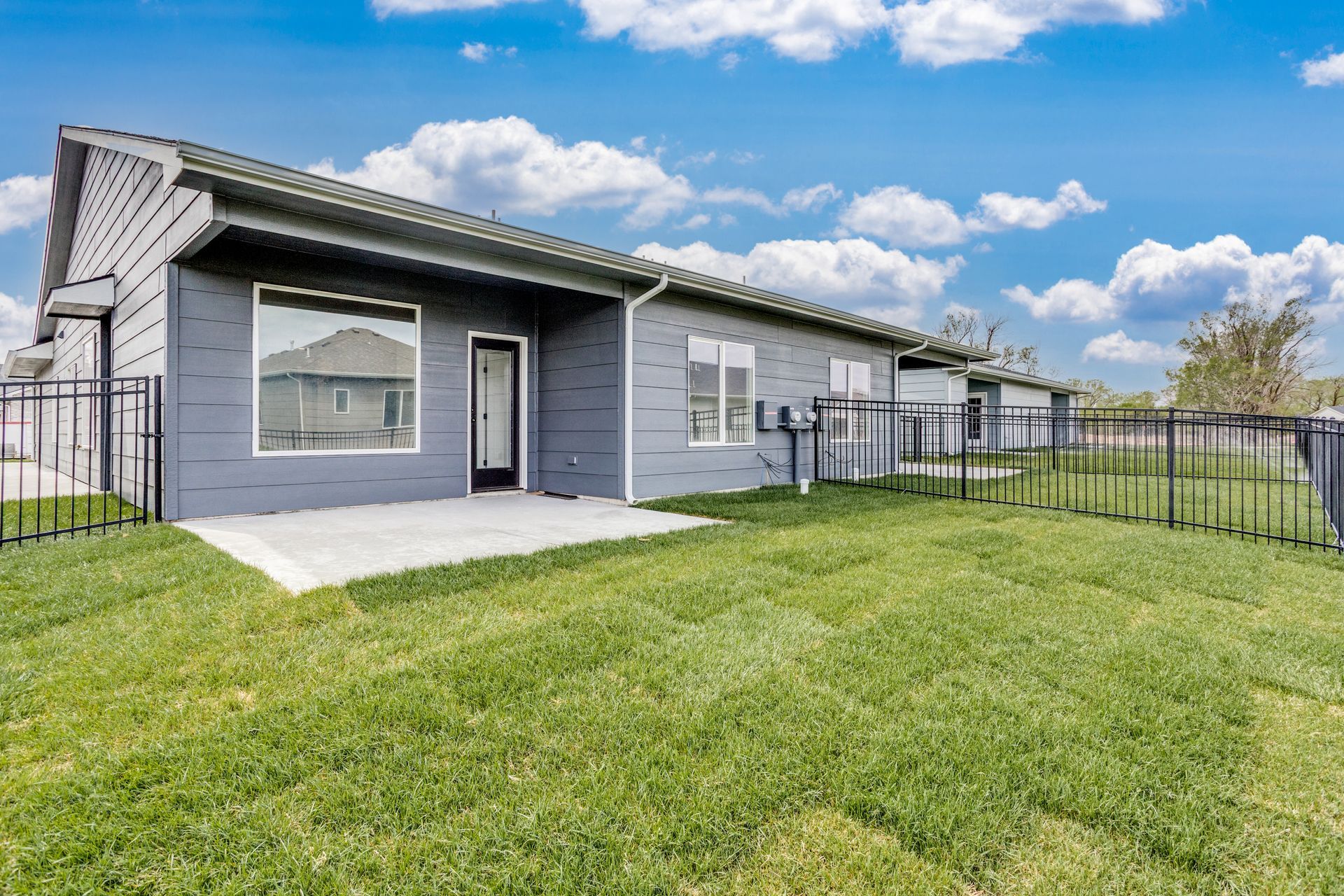 The backyard of a house with a large lawn and a fence.