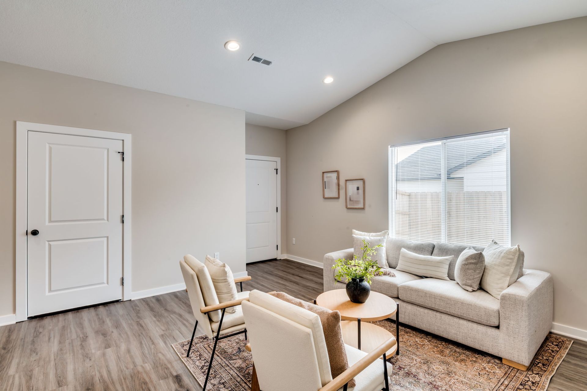 A living room with a couch , chairs , and a window.