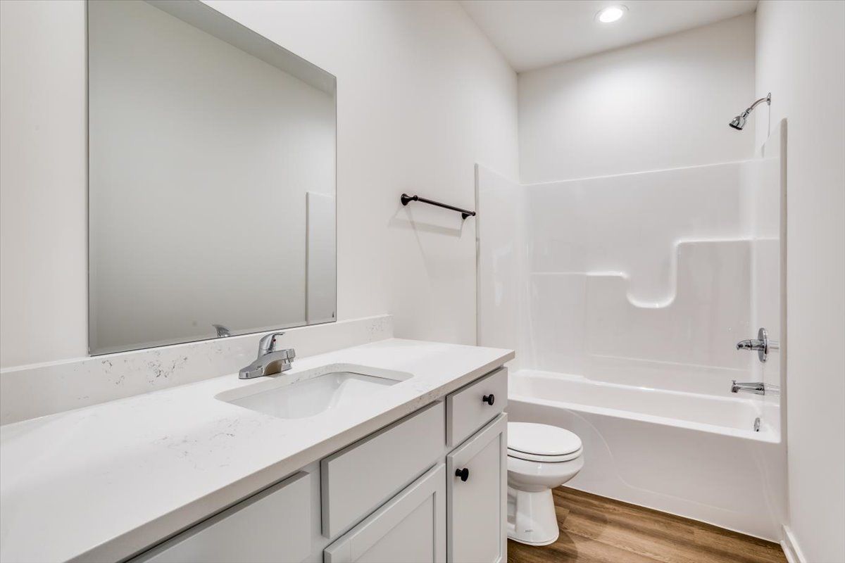 A bathroom with a sink , toilet , bathtub and mirror.