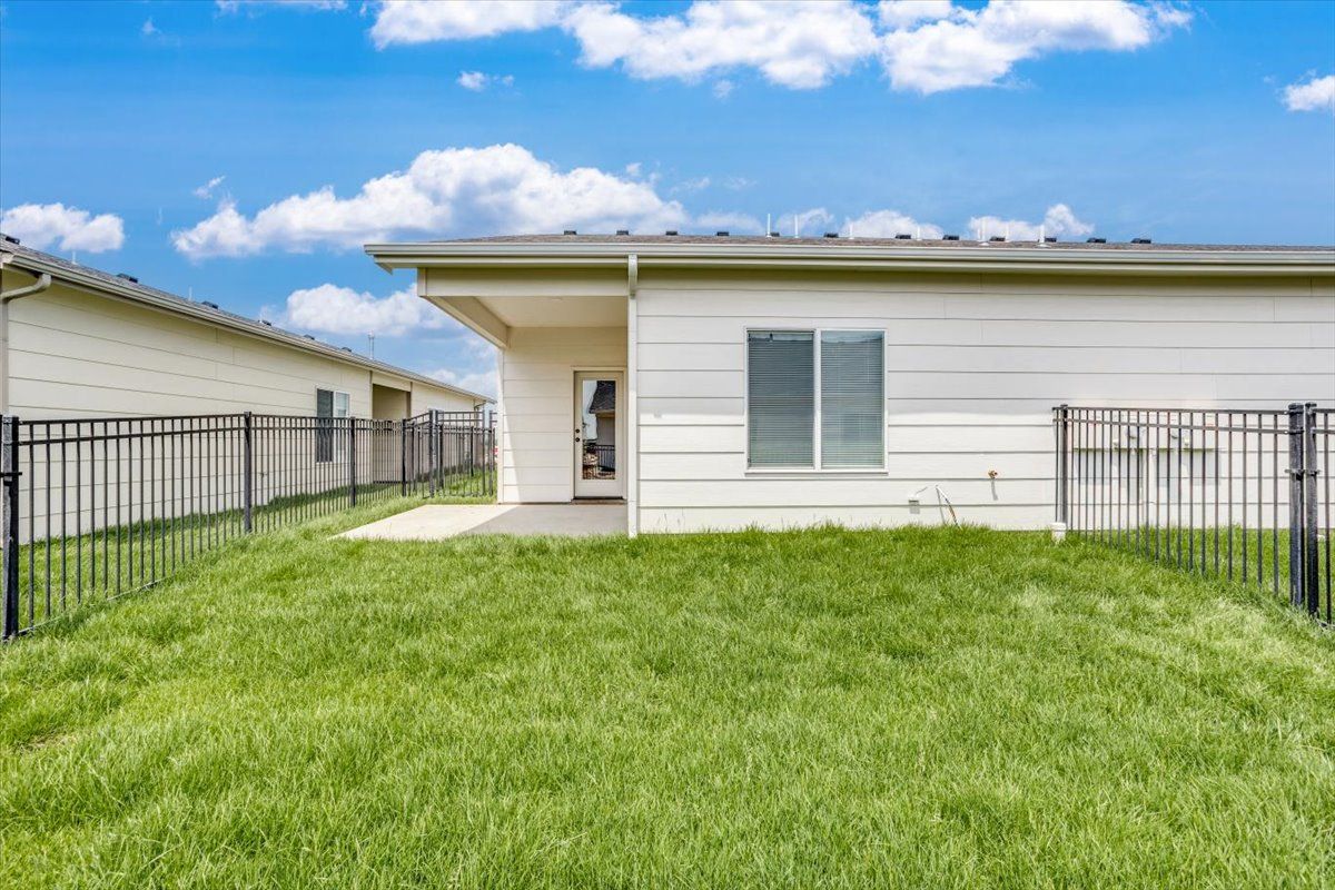 The backyard of a house with a fence and a lot of grass.