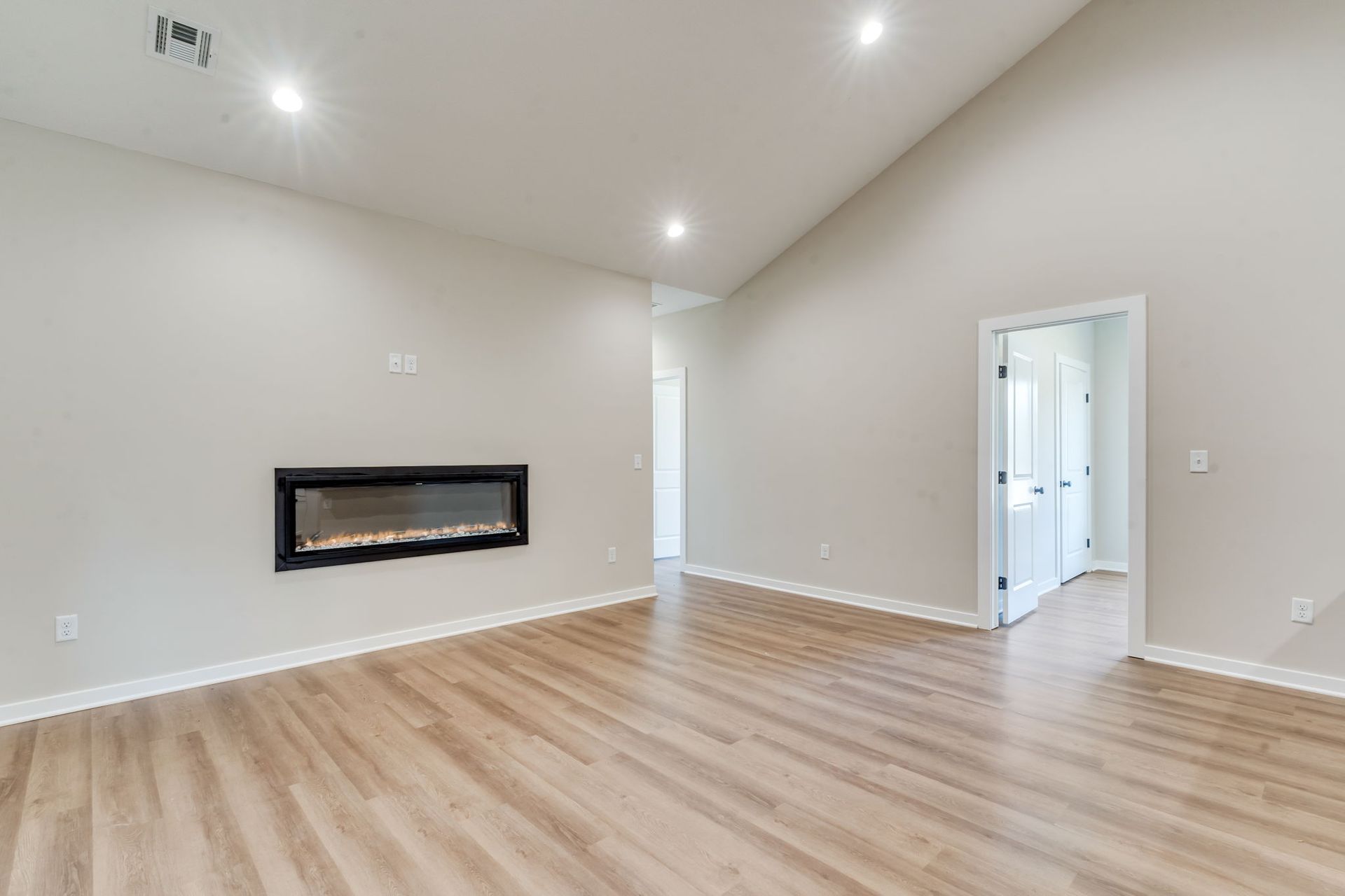 An empty living room with hardwood floors and a fireplace.