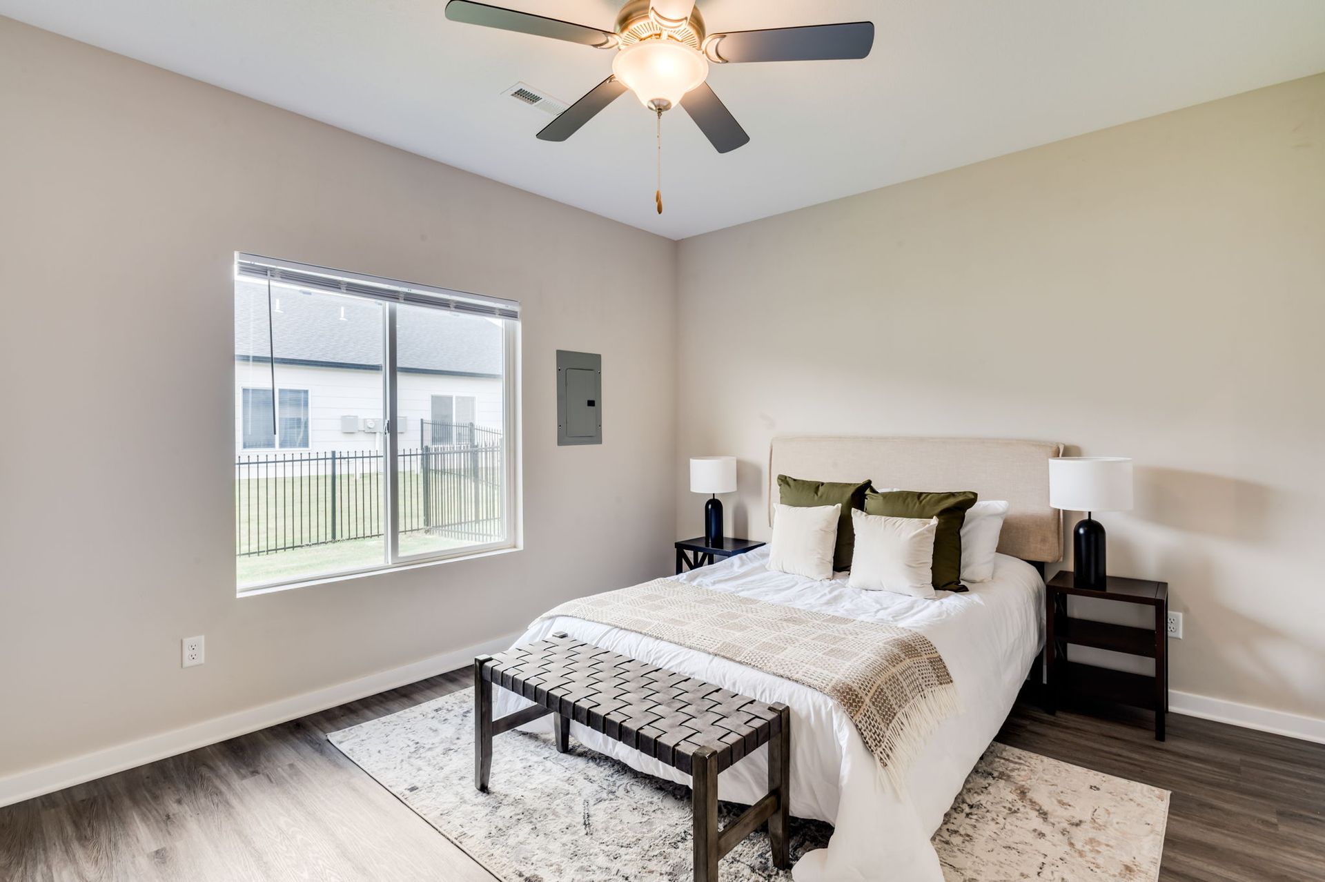 A bedroom with a bed , nightstands , lamps and a ceiling fan.