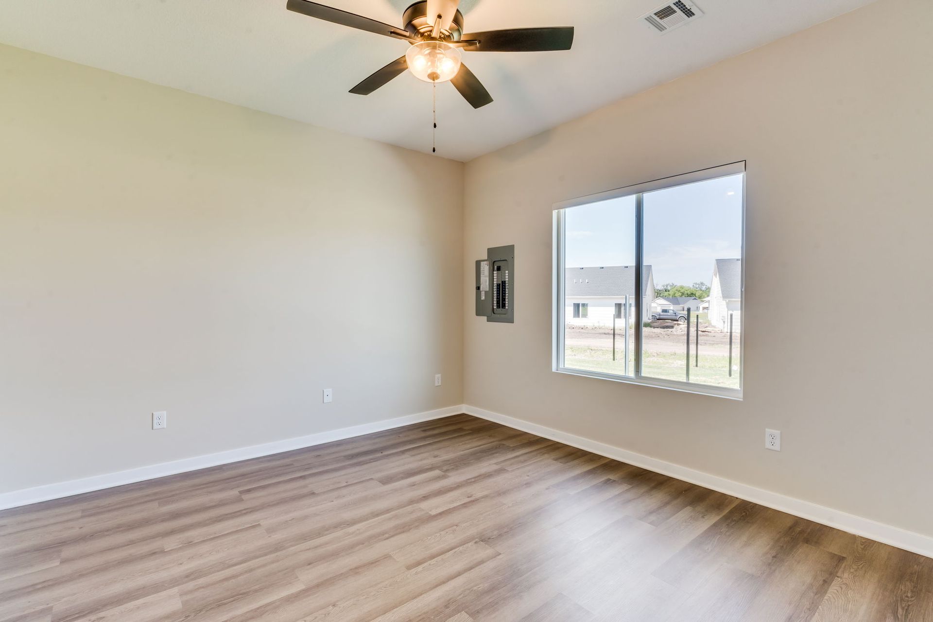 An empty living room with hardwood floors and a ceiling fan.