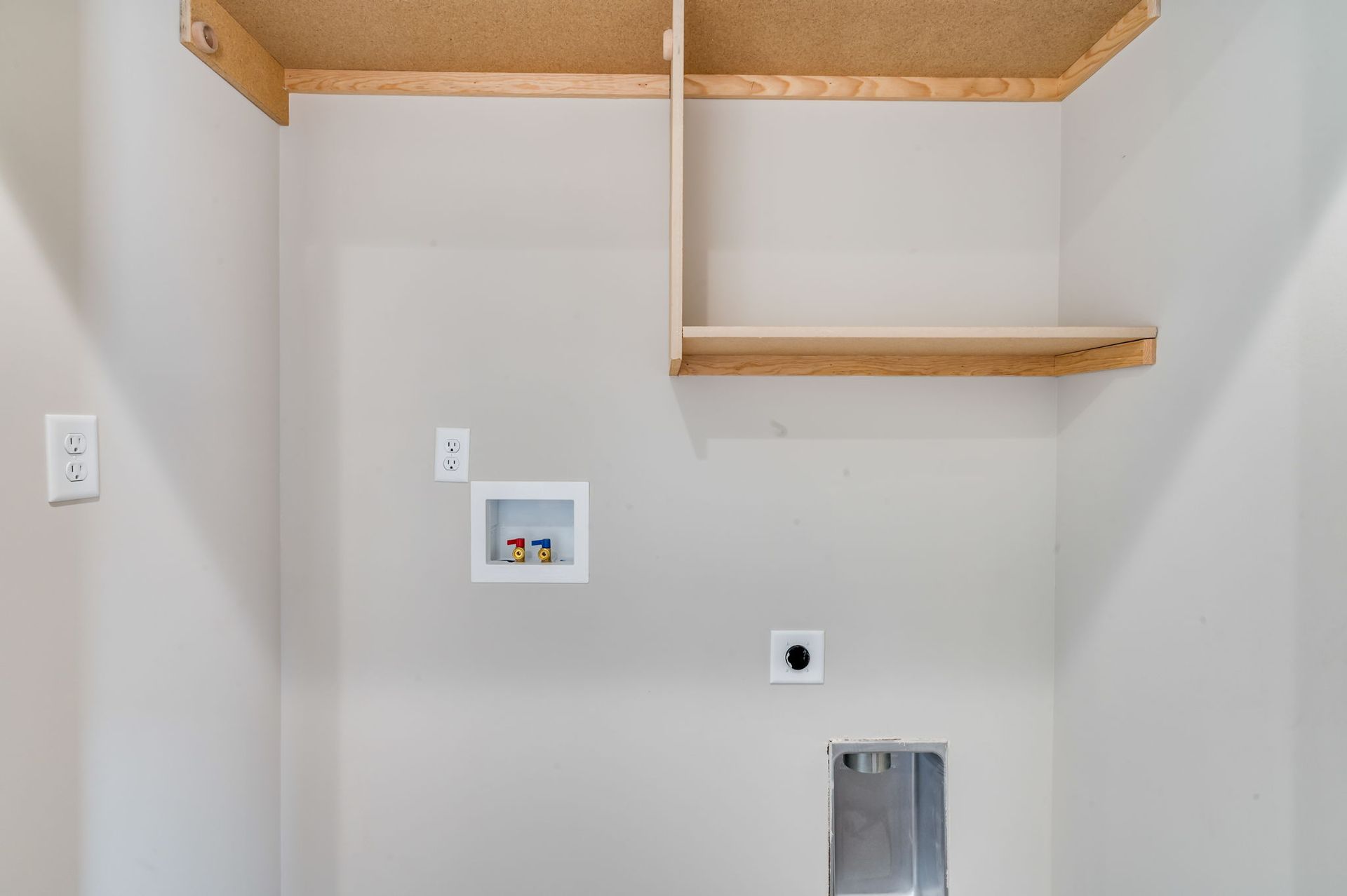 A laundry room with a washer and dryer and a shelf.